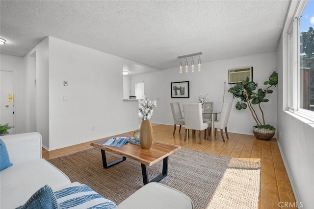 living room featuring a wall unit AC, a textured ceiling, and wood-type flooring