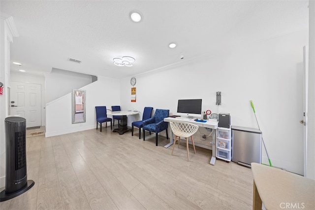 office with light wood-type flooring and a textured ceiling