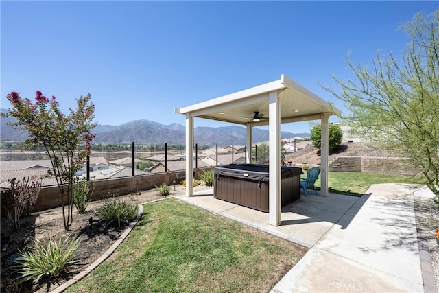 view of yard featuring ceiling fan, a mountain view, a patio, and a hot tub