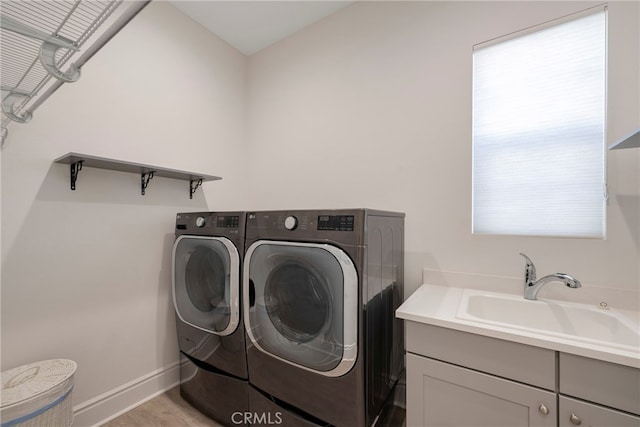 laundry area with cabinets, a wealth of natural light, sink, and washing machine and dryer