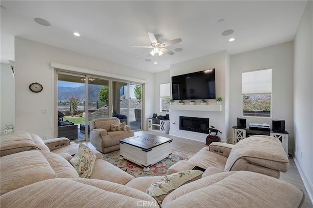 living room with ceiling fan, light wood-type flooring, and a healthy amount of sunlight