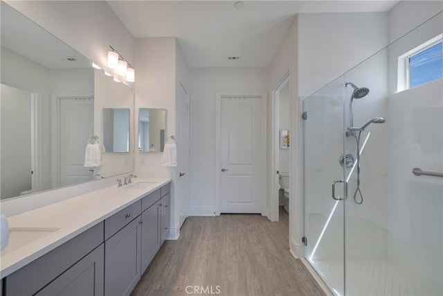 bathroom featuring hardwood / wood-style floors, a shower with door, vanity, and toilet