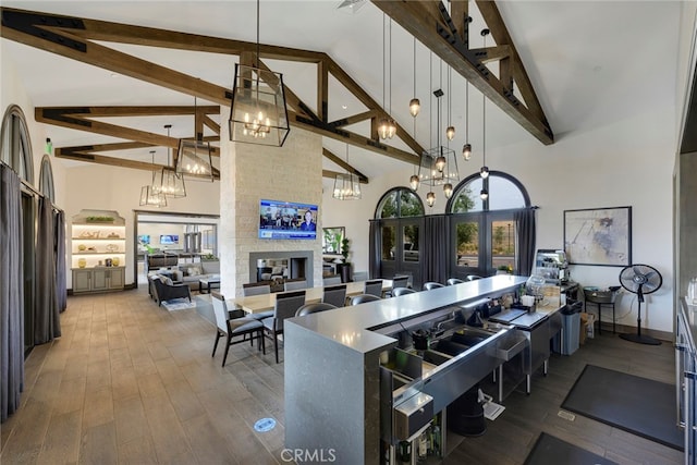 kitchen with hanging light fixtures, high vaulted ceiling, an inviting chandelier, a fireplace, and hardwood / wood-style floors