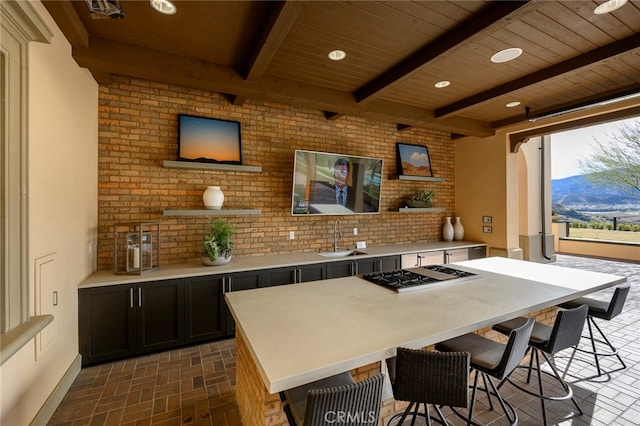 kitchen with a mountain view, beamed ceiling, a breakfast bar area, sink, and stainless steel gas cooktop