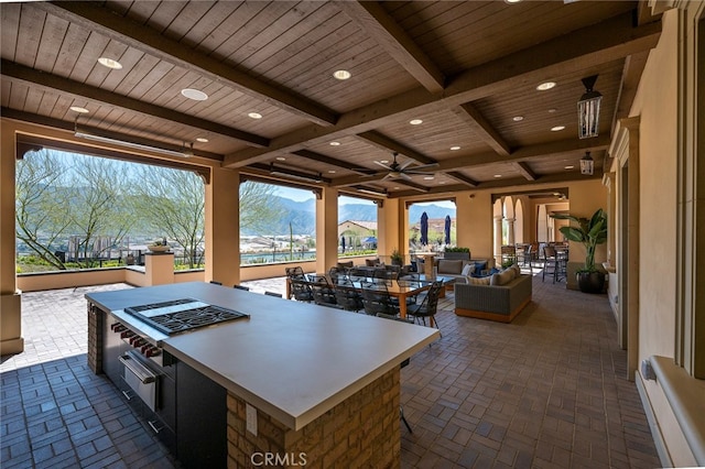 kitchen with ceiling fan, a mountain view, wood ceiling, beam ceiling, and a spacious island