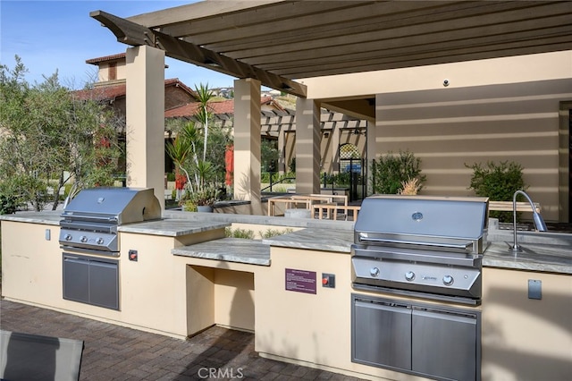 view of patio / terrace with area for grilling, sink, a grill, and a pergola