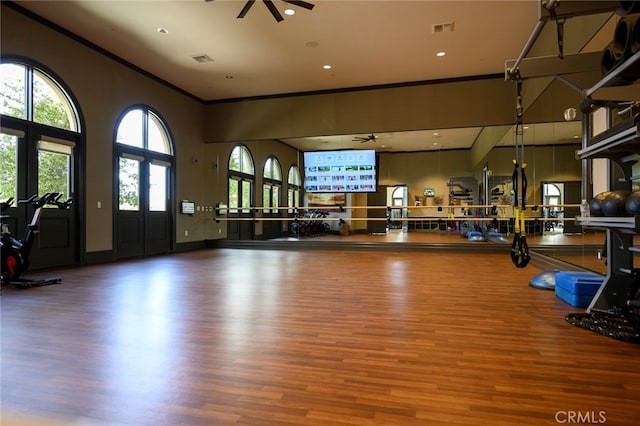 workout area featuring ceiling fan, crown molding, hardwood / wood-style floors, and a high ceiling