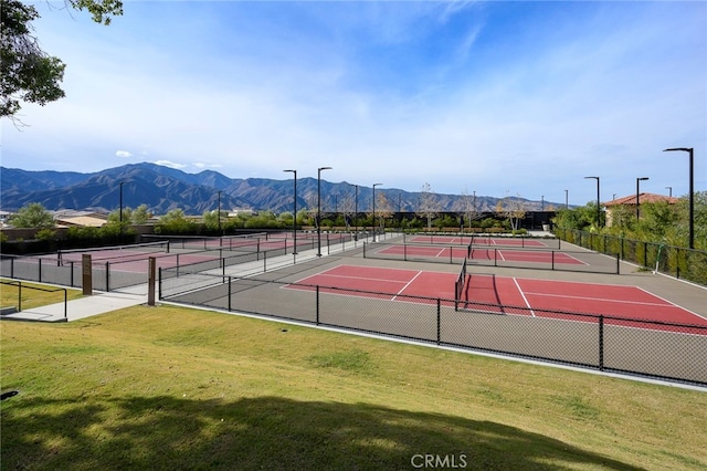 view of tennis court with a mountain view and a yard