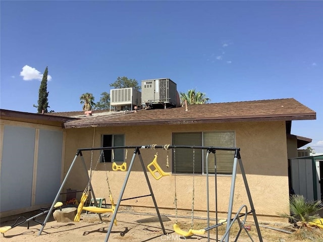 5645 Cahuilla Ave Unit 29, Palms, CA 92277 - rear view of property featuring stucco siding, roof with shingles, and a playground