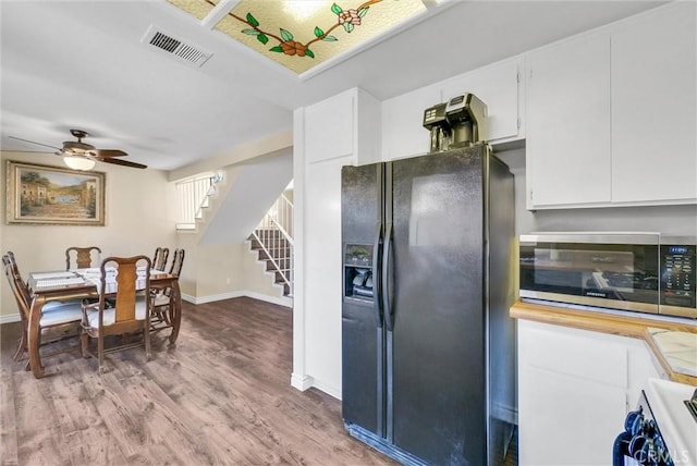 kitchen featuring stove, black refrigerator with ice dispenser, white cabinets, hardwood / wood-style flooring, and ceiling fan