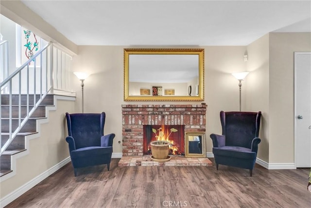 living area with wood-type flooring and a brick fireplace