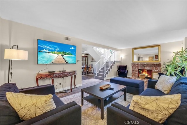 living room with a brick fireplace, ceiling fan, and light hardwood / wood-style flooring