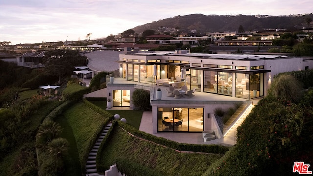 back house at dusk with a mountain view and a patio area