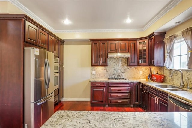 kitchen featuring light stone countertops, sink, dark wood-type flooring, stainless steel appliances, and ornamental molding