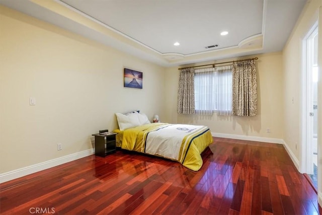 bedroom with hardwood / wood-style floors and a raised ceiling