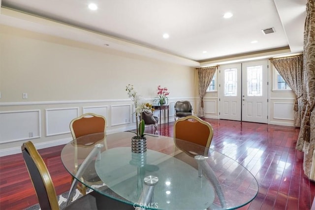 dining area featuring wood-type flooring, a raised ceiling, and french doors