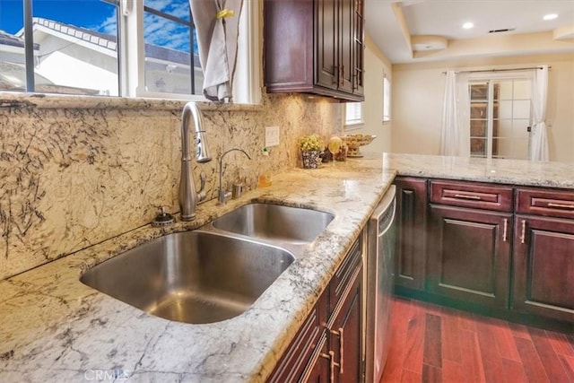 kitchen featuring decorative backsplash, light stone counters, stainless steel dishwasher, sink, and dark hardwood / wood-style floors