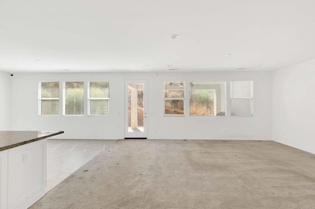 unfurnished room featuring light carpet and a wealth of natural light