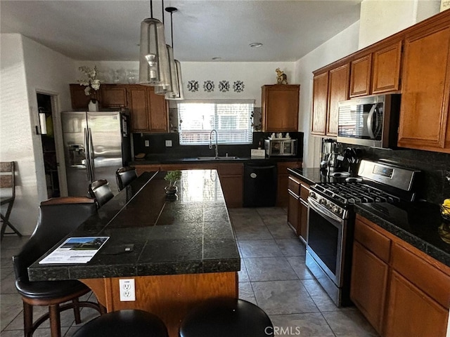 kitchen featuring hanging light fixtures, sink, appliances with stainless steel finishes, a center island, and a kitchen bar