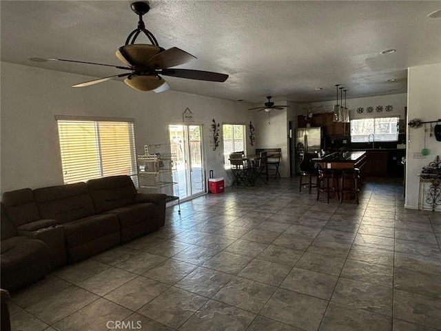 living room featuring a textured ceiling, ceiling fan, plenty of natural light, and sink