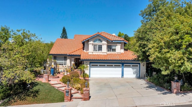 mediterranean / spanish-style home featuring a tile roof, driveway, and stucco siding