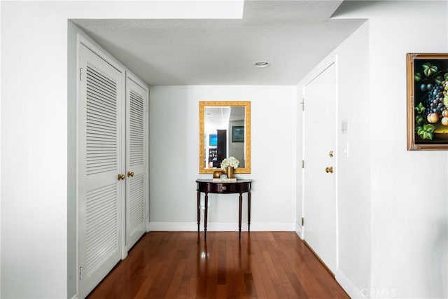 hall with a textured ceiling and dark hardwood / wood-style floors