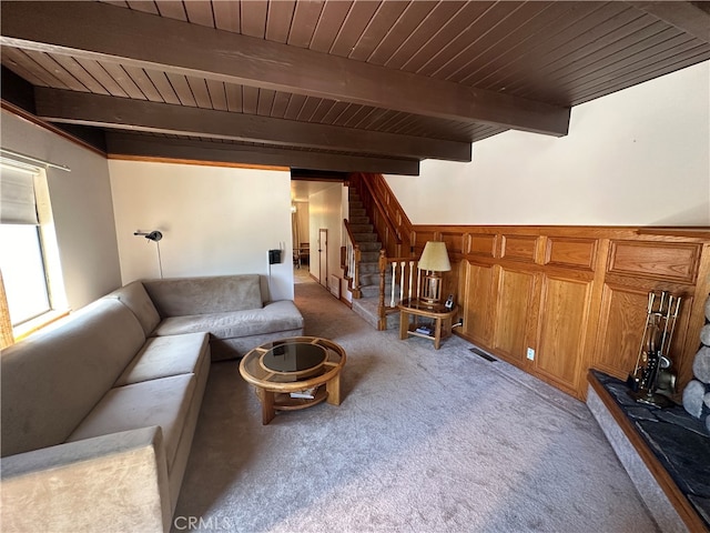 living room featuring light colored carpet, beam ceiling, and wooden ceiling