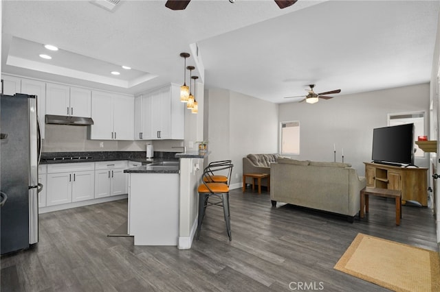 kitchen with pendant lighting, a breakfast bar, white cabinets, dark hardwood / wood-style floors, and stainless steel fridge