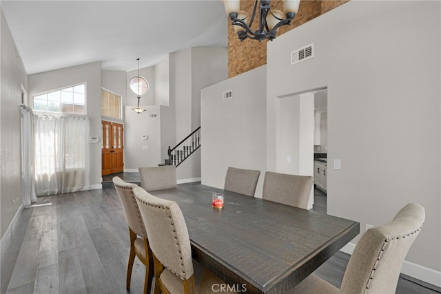 dining area featuring high vaulted ceiling, dark hardwood / wood-style floors, and a notable chandelier