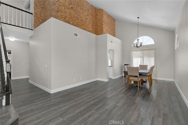 dining space featuring dark hardwood / wood-style flooring, an inviting chandelier, and high vaulted ceiling