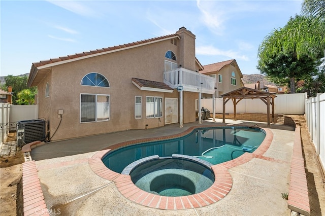 rear view of house with a swimming pool with hot tub, a balcony, a patio, and cooling unit