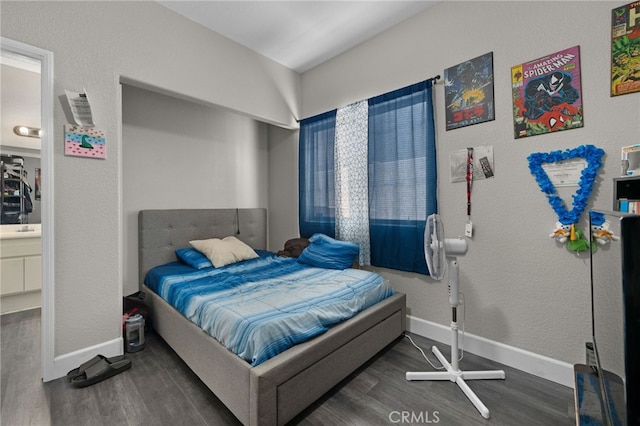 bedroom with connected bathroom and dark hardwood / wood-style floors