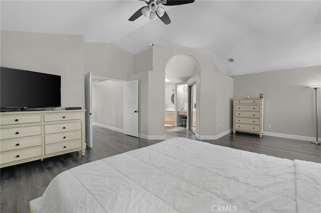 bedroom with ensuite bathroom, ceiling fan, dark wood-type flooring, and vaulted ceiling