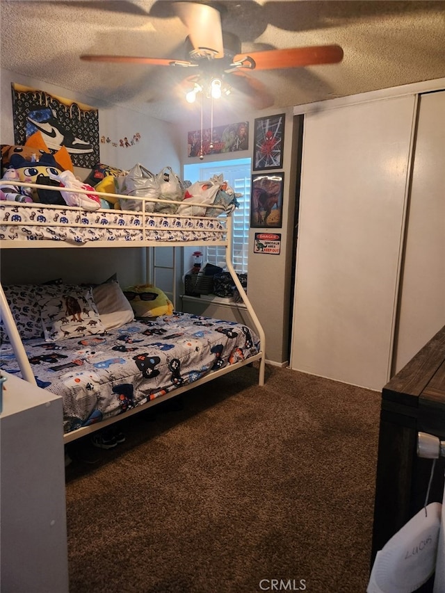 carpeted bedroom with ceiling fan and a textured ceiling