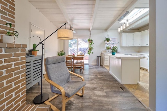 kitchen featuring pendant lighting, white cabinetry, a kitchen island, beam ceiling, and wood-type flooring