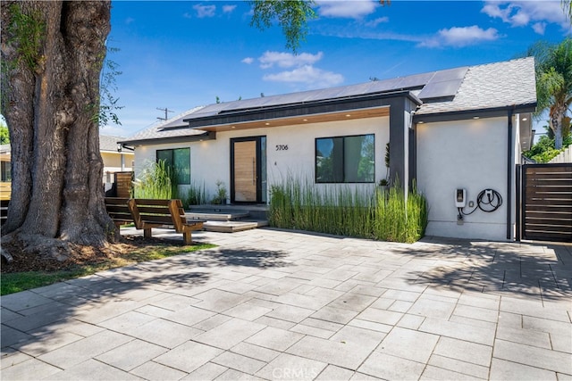 view of front facade with a patio and solar panels