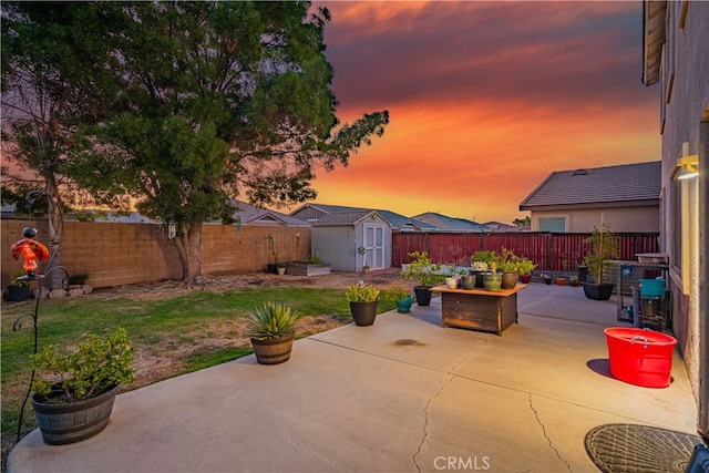 patio terrace at dusk featuring a storage shed