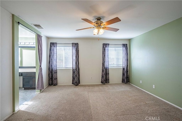 carpeted empty room with ceiling fan and plenty of natural light