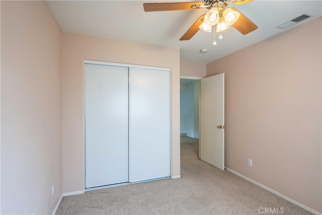 unfurnished bedroom featuring ceiling fan, a closet, and light carpet