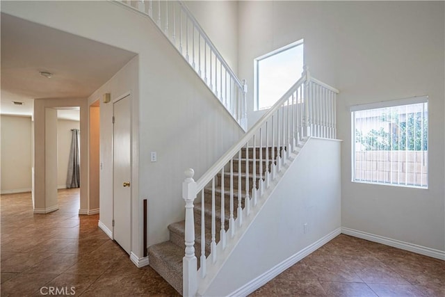 staircase with tile patterned flooring and a towering ceiling