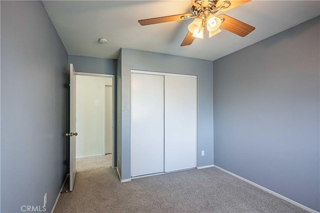 unfurnished bedroom featuring ceiling fan, light colored carpet, and a closet