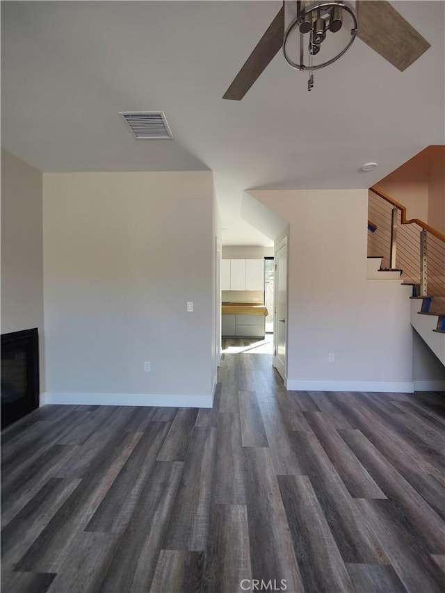 unfurnished living room featuring ceiling fan and dark hardwood / wood-style flooring