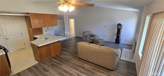 kitchen featuring dark wood-type flooring, kitchen peninsula, tile countertops, and ceiling fan