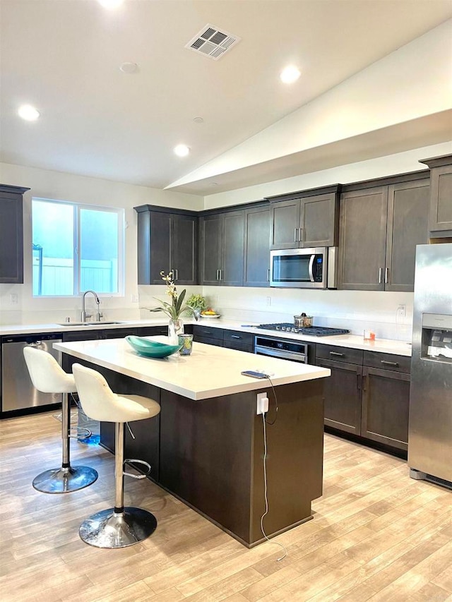 kitchen featuring lofted ceiling, a kitchen island, sink, and stainless steel appliances