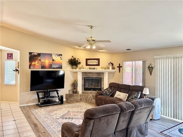 living room featuring a tile fireplace, hardwood / wood-style floors, ceiling fan, and lofted ceiling