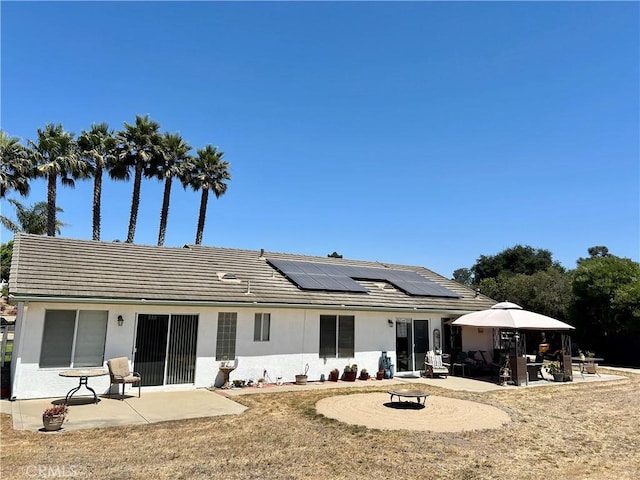 back of property featuring solar panels and a patio area