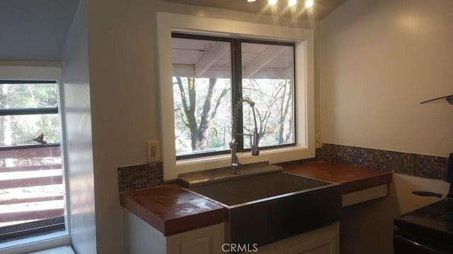 kitchen with lofted ceiling, stove, and sink