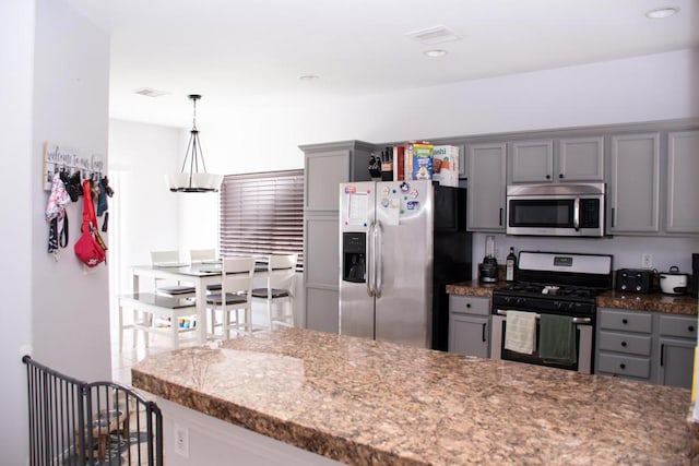 kitchen featuring gray cabinetry, light stone countertops, pendant lighting, a breakfast bar area, and appliances with stainless steel finishes