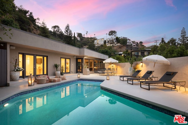 pool at dusk featuring a patio area