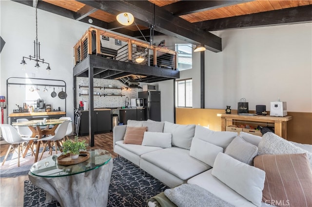 living room with wood ceiling, wood-type flooring, sink, a towering ceiling, and beam ceiling